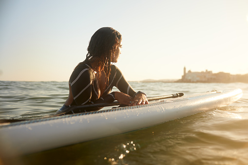 A woman is resting on a floating Paddle surfboard.