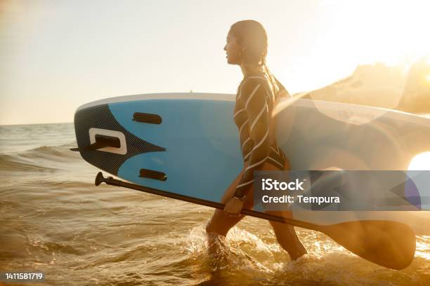A Beautiful Woman Is Entering The Water To Paddle Surf Stock Photo - Download Image Now