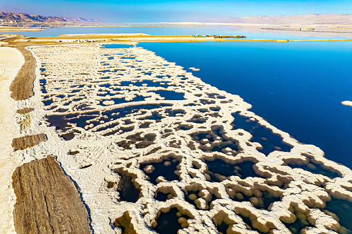 Magic of the Dead Sea. Evaporated salt forms bizarre patterns on the blue water. The photo was taken from a drone. Cold sunny winter day. Israel