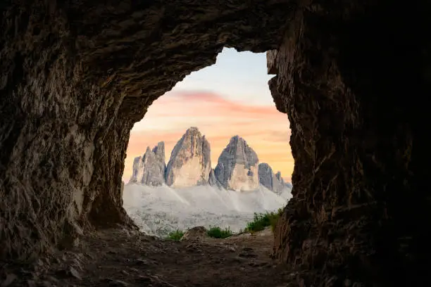 Photo of Stunning view of the Three Peaks of Lavaredo, (Tre cime di Lavaredo) during a beautiful sunset framed by a cave. The Three Peaks of Lavaredo are the undisputed symbol of the Dolomites, Italy.