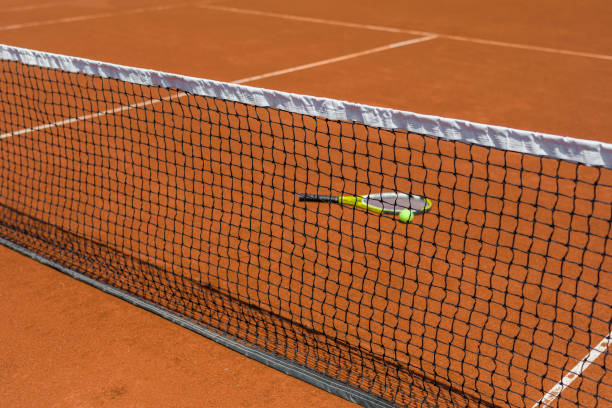 Part of empty used red clay tennis court playground surface with white lines closeup