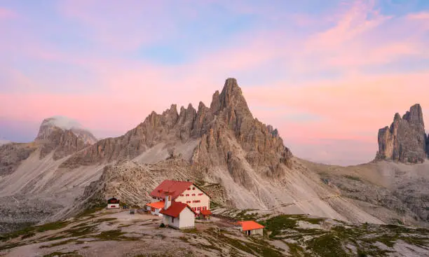 Photo of Stunning view of a mountain hut during a beautiful sunset with Mt Paterno in the background. The Three Peaks of Lavaredo are the undisputed symbol of the Dolomites, Italy.