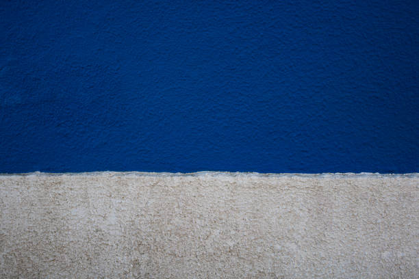 Old concrete rough wall texture painted in two horizontal strips of blue and white colors. Abstract background with empty space for text
