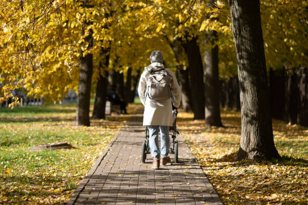 istock Mother walking in park with a stroller. 1411607992