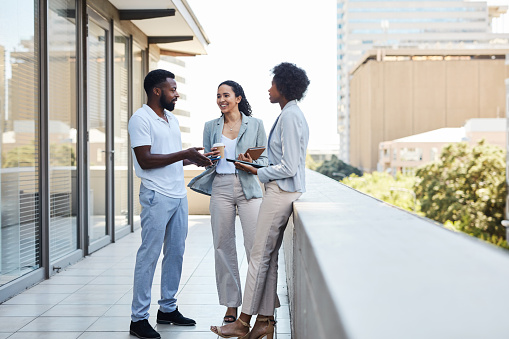 Young business people talking and brainstorming on the rooftop of an office building in the city. Confident and happy colleagues planning and collaborating on a new project while discussing ideas