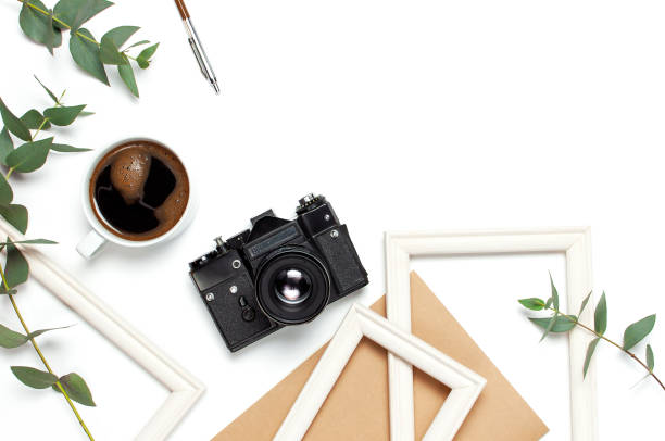 istock Photo frame old retro camera notebook diary cup of coffee pens eucalyptus leaves on white background. Flat lay top view copy space. Stylish minimal composition artwork mockup Feminine desk workspace 1411611849
