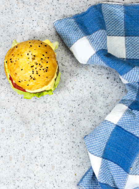homemade burger with cheese and meat, tomato and salad with blue plaid napkin