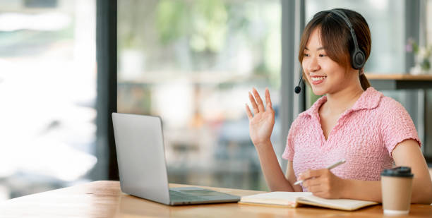 istock Young asian woman having video call via laptop computer at co-workspace. 1411613436