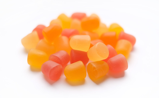 Close-up texture of orange and yellow multivitamin gummies on white background.  Healthy lifestyle concept.