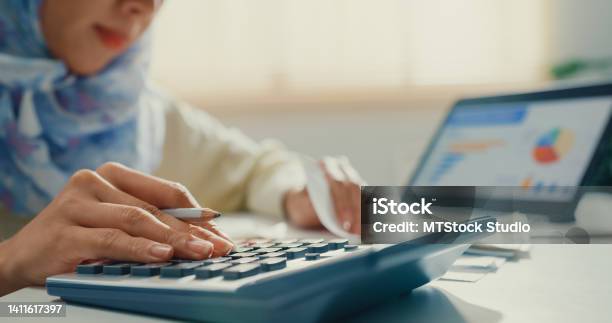 Closeup Asian Muslim Woman With Hijab Using Tablet Calculator Focus On Utility Bills Calculate Check Credit Card Receipt Monthly Expense Bill In Living Room At House Stock Photo - Download Image Now