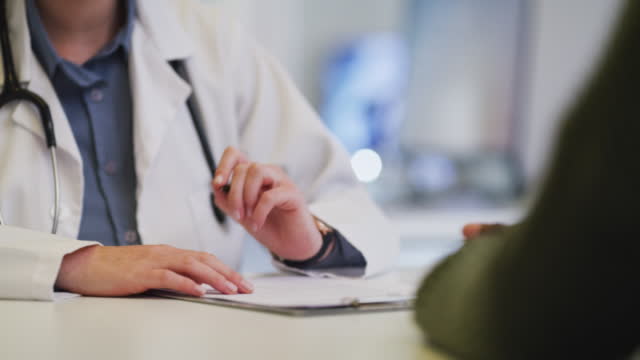Closeup of doctor writing script and record notes while discussing diagnosis with patient during checkup and consultation in medical office. Physician prescribing treatment medicine during appointment