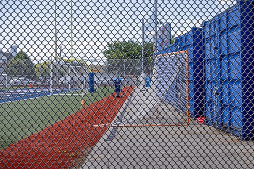 Wire fencing protecting a sports field belonging to the Long Island City High School in Long Island City which is a part of Queens and is a mixture of new and old, small industries and residential areas close to Manhattan, New York