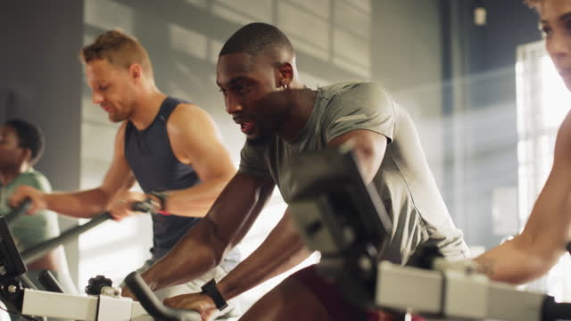 Burning calories and increasing endurance. Fit young man exercising on a exercising bike in a gym. Determined and focused muscular guy sweating while doing cardio training with aerobics equipment.