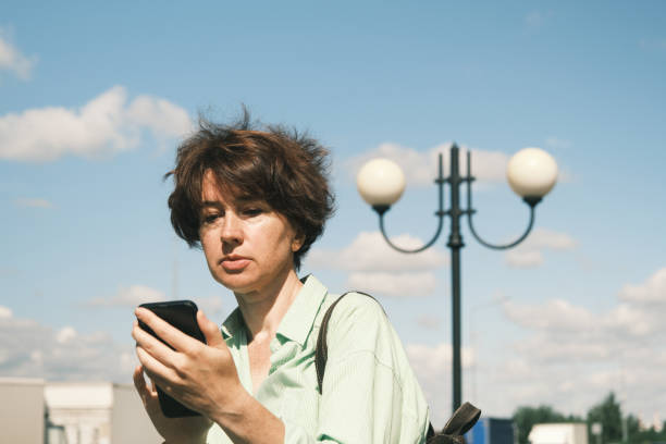 istock Woman is using her phone on town street 1411619257