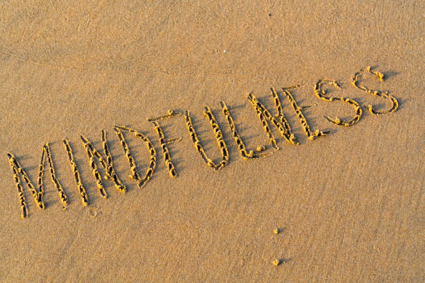 foamy sea water and Inscription mindfulness on the sandy beach stock photo