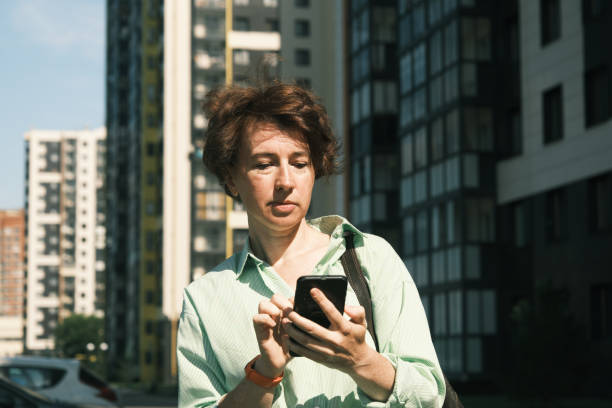 istock Woman is using her phone on town street 1411619787