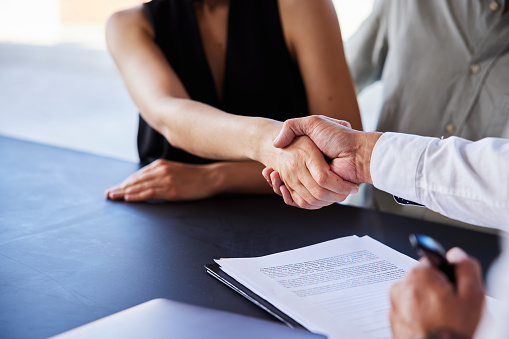 Close-up of a young couple shaking hands with a broker after signing a contract for their home loan