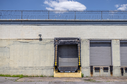 Old industrial building with gates close by metal blinds in 12th Street in Long Island City which is a part of Queens and is a mixture of new and old, small industries and residential areas close to Manhattan, New York