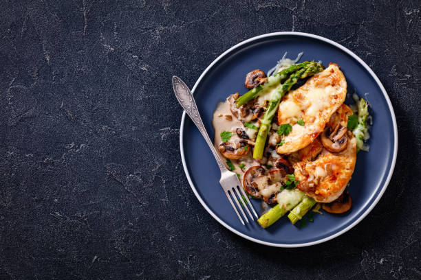Chicken Madeira served on plate, top view Chicken Madeira, juicy chicken breasts and mushrooms in a madeira cream sauce under melty mozzarella cheese and asparagus on plate on concrete table, flat lay, free space madeira sauce stock pictures, royalty-free photos & images