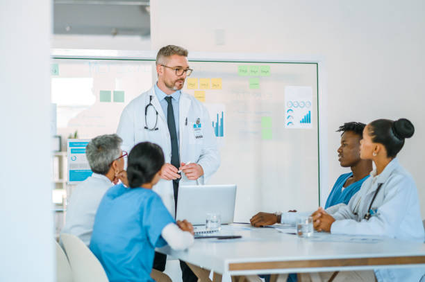 A team of healthcare professionals sitting in a meeting and listening to a presentation. A group of doctors having a discussion inside hospital boardroom. Male medical leader addressing his coworkers médico cirujano masculino entrenando a sus compañeros de trabajo. un equipo de profesionales de la salud sentados en una reunión y escuchando una presentación. un grupo de médicos teniendo una discusión dentro de la sala de juntas del hospital.