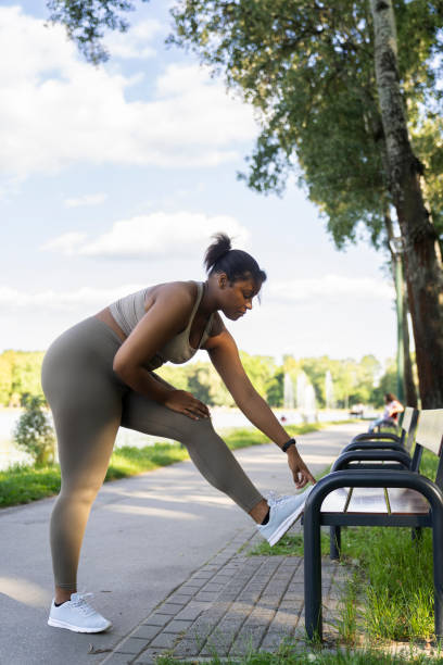 istock Plus sized African-American woman exercising at the park using a bench in a summer day 1411627632