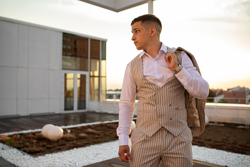 Elegant handsome man posing on the rooftop during sunset