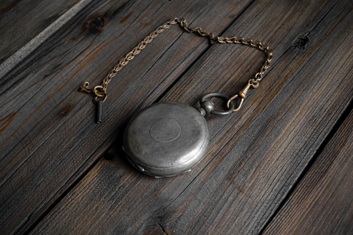 Silver pocket watch on a wooden table. Pocket watches on a silver chain. Closed pocket watch.