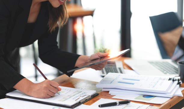 istock Businesswoman working on digital tablet and document on her desk, analyzing financial and marketing graph chart. 1411629766