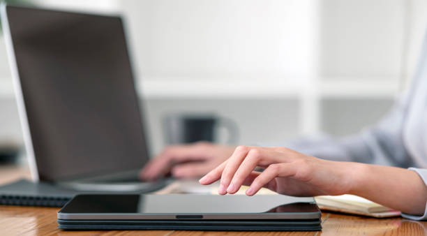 istock Closeup woman hands using digital tablet and laptop computer at office. 1411630794