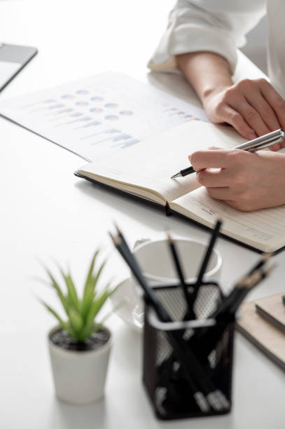 businesswoman writing note on her notebook at office. - note pad desk office meeting imagens e fotografias de stock