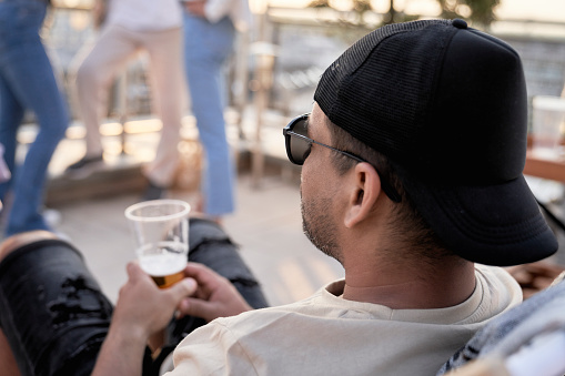 Close up of latino man in cap sitting at the party outdoors