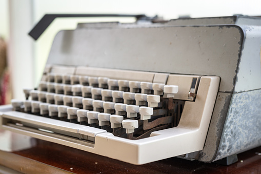 A classic style typewriter which is placed on working desk. Equipment object photo. Close-up and selective focus.