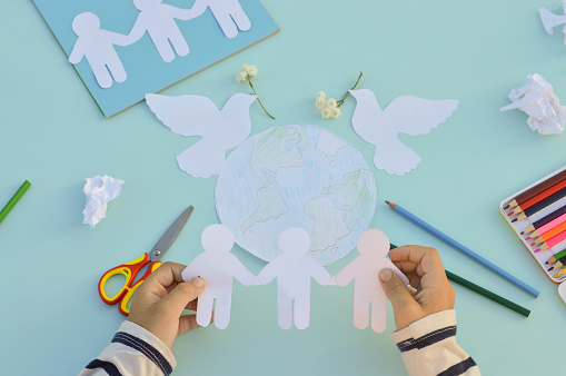 Un primer plano de las manos de un niño que hace una postal para el Día Internacional de la Paz, manualidades con sus propias manos, hágalo usted mismo, qué hacer con los niños. photo