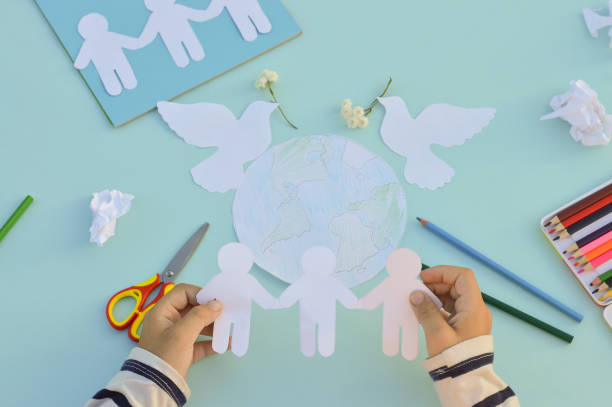 a close-up of the hands of a child who makes a postcard for the international day of peace, crafts with his own hands, do it yourself, what to do with children. - earth globe human hand symbols of peace imagens e fotografias de stock