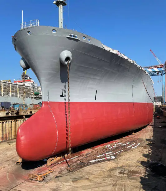 Dry-cargo ship in dry dock for repairs and maintenance at a shipyard. Stern bottom of the ship laying on the structure support in floating dry dock
