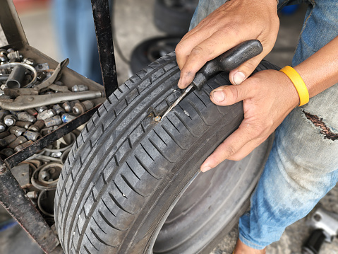 The car's wheel was treaded on by a screw nut, causing the tire to flatten. Must be repaired by skilled technicians to ensure safe driving on the road.
