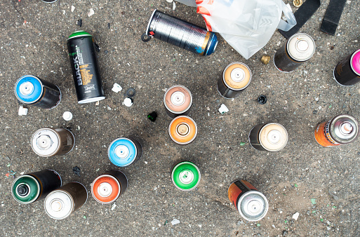 Glasgow, Scotland - A collection of aerosol spray paint cans in a variety of colours on a city street.