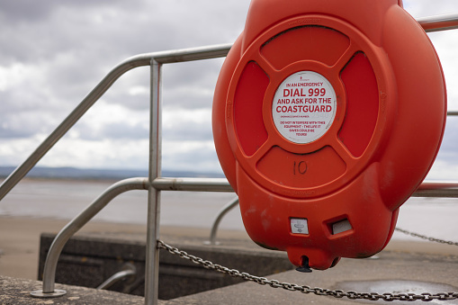 2nd July, 2022 - Enclosed life belt with safety instruction on the seafront of the seaside town of Burnham-on-Sea on the Bristol Channel coast in the south of England
