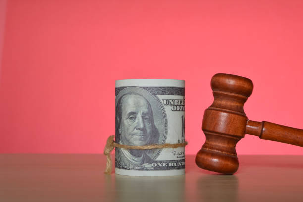 istock Judge gavel and money banknotes isolated on a red background 1411646040