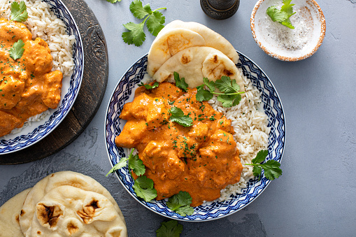 Chicken tikka masala, cooked marinated chicken chunks in spiced curry sauce, served over rice and with naan bread top view