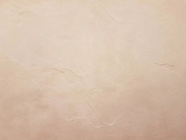 A sand beige colour stock photo of a newly plastered wall showing a smooth and semi rough texture detail.