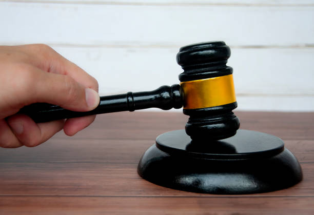 istock Hand holding lawyer gavel on wooden table background. 1411652704