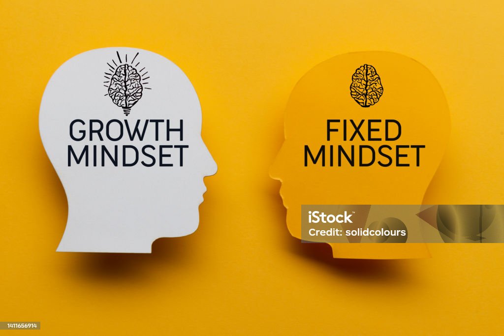 Growth Mindset vs Fixed Mindset Paper heads and words on yellow background. Attitude Stock Photo