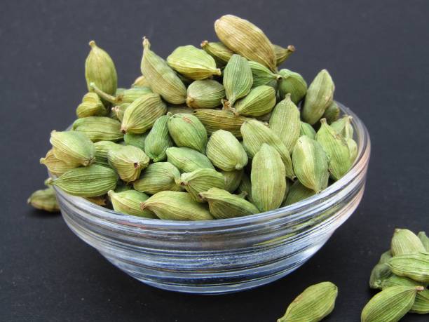 istock Green Cardamom in a glass bowl on black background 1411657172