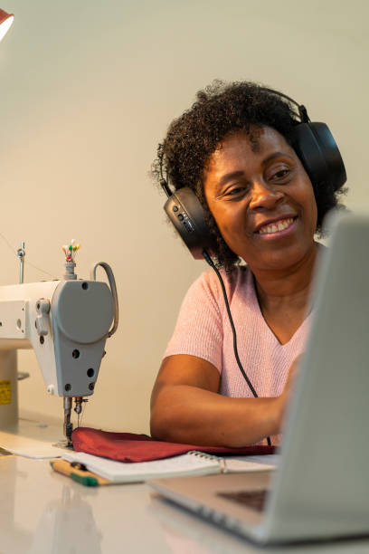 istock Afro woman is in her sewing workshop taking online design classes through her laptop 1411658678