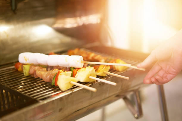 pinchos de malvavisco a la parrilla en barbacoa con varias carnes en una fiesta con la mano borrosa - party barbecue grill burning healthcare and medicine fotografías e imágenes de stock