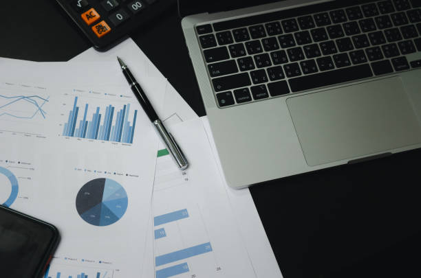istock Business document finance graph and chart report analysis marketing and accounting with computer laptop on desk at office. 1411660478