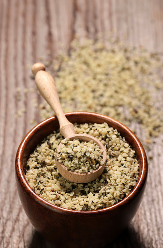 Organic shelled hemp seeds in a bowl on wooden background. Copy space. Close-up.