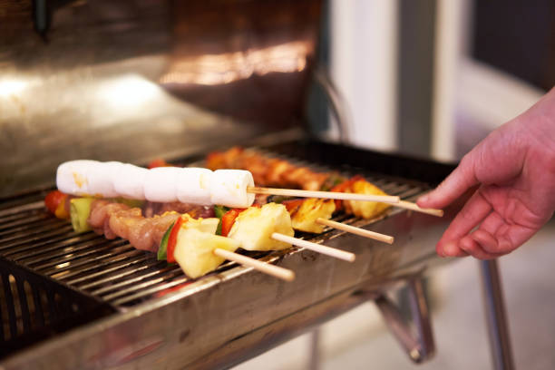 pinchos de malvavisco a la parrilla en barbacoa con varias carnes en una fiesta con la mano borrosa - party barbecue grill burning healthcare and medicine fotografías e imágenes de stock