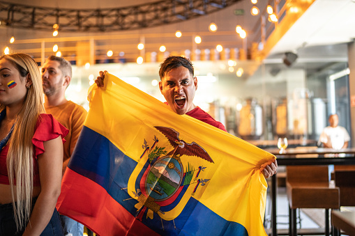 Fan man celebrating winning holding Ecuadorean flag at bar
